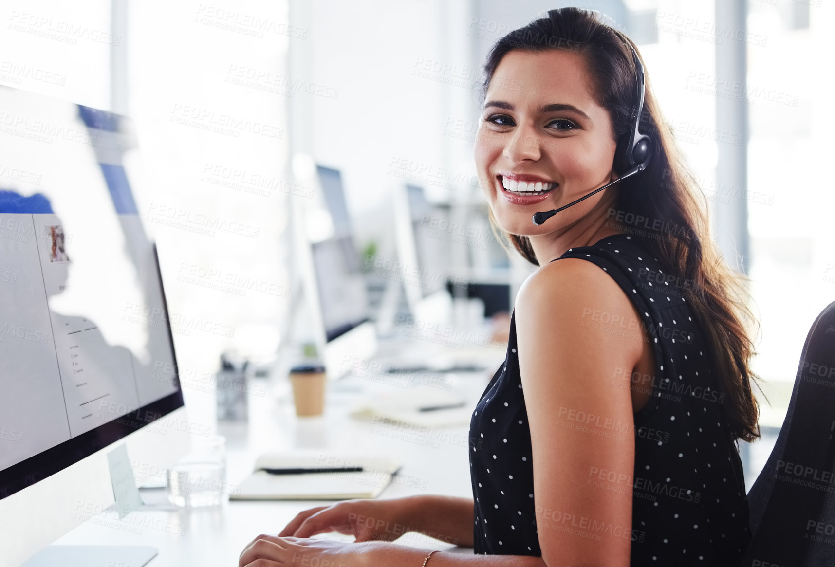 Buy stock photo Shot of a young woman using a computer and headset in a modern office