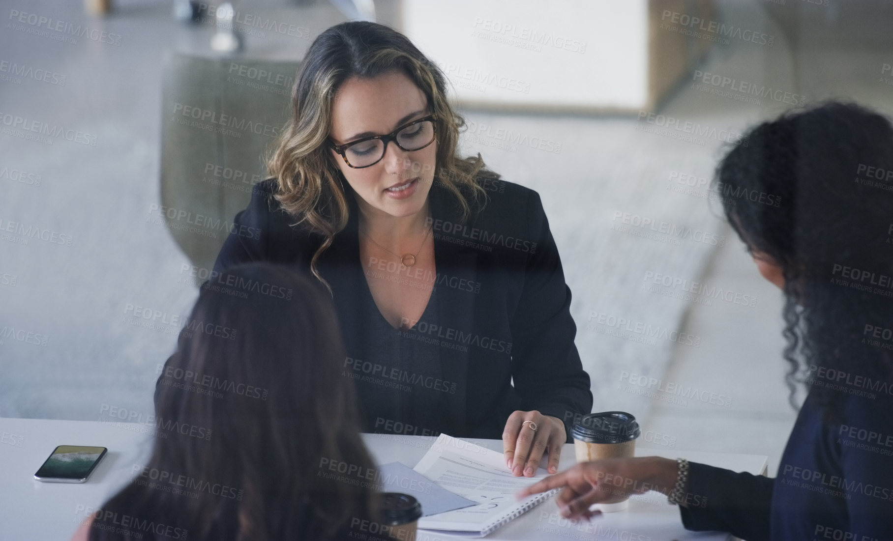 Buy stock photo High angle shot of three young businesswoman sitting in the boardroom during a management meeting