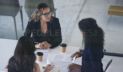 Buy stock photo High angle shot of three young businesswoman sitting in the boardroom during a management meeting