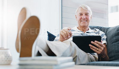 Buy stock photo Shot of a senior man using a digital tablet on the sofa at home