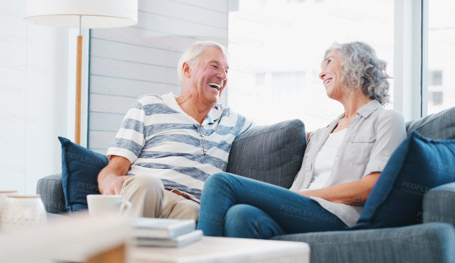 Buy stock photo Senior couple, home and laughing on sofa in living room on break, bonding and relax. People, relationship and happy for love with gossip for conversation, chat and funny memories for retirement