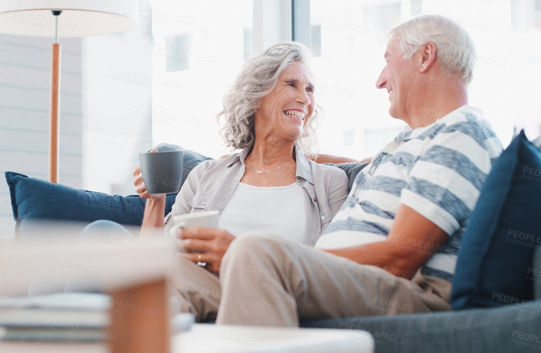 Buy stock photo Happy, talking and old couple with coffee on sofa for bonding, commitment and marriage. Retirement, home and senior man with woman with beverage for conversation, relationship and relax together
