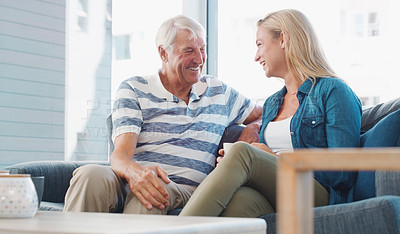 Buy stock photo Shot of a young woman enjoying a coffee break with her father at home