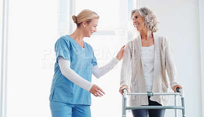 Buy stock photo Shot of a senior woman using a walker with the assistance of a young nurse