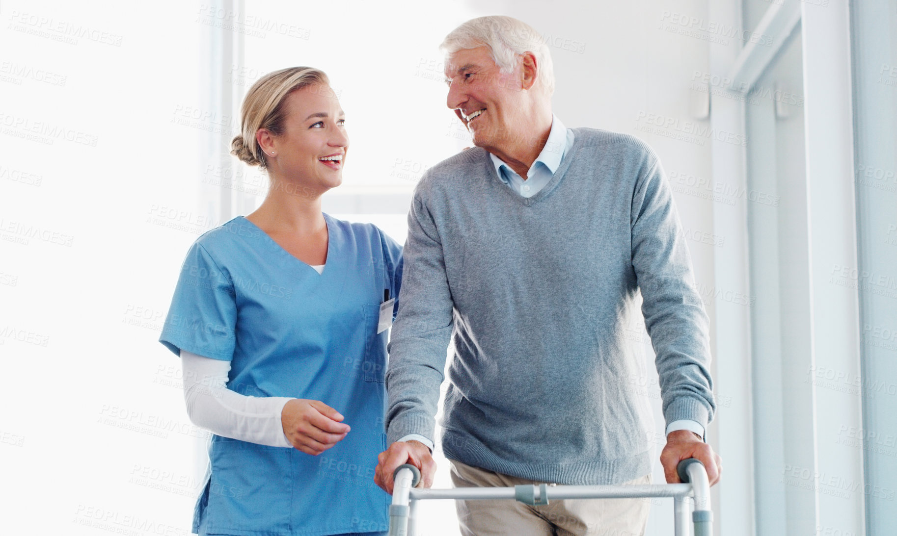 Buy stock photo Shot of a senior man using a walker with the assistance of a young nurse