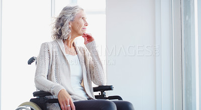Buy stock photo Shot of a senior woman in a wheelchair looking thoughtfully out of a window