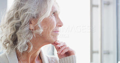 Buy stock photo Shot of a senior woman looking thoughtfully out of a window