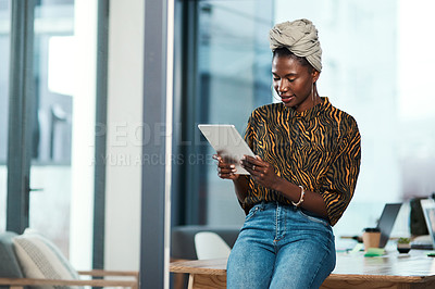 Buy stock photo Cropped shot of an attractive young businesswoman sitting alone in her office and using a tablet