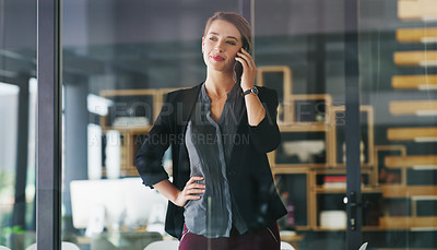 Buy stock photo Cropped shot of an attractive young businesswoman standing alone in her office and talking on her cellphone