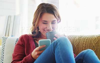 Buy stock photo Cropped shot of an attractive young woman sitting and using her cellphone while drinking a cup of coffee at home
