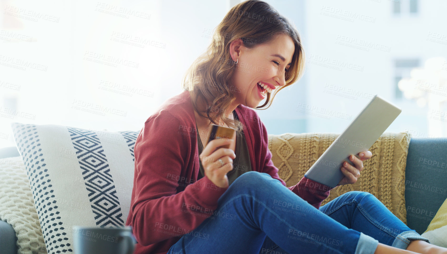 Buy stock photo Cropped shot of an attractive young woman sitting on her sofa and using her tablet for online shopping