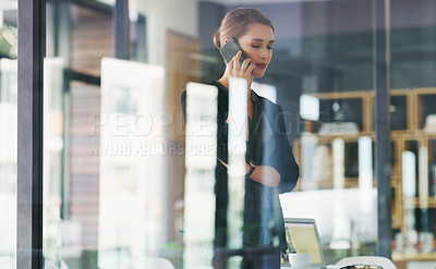 Buy stock photo Cropped shot of an attractive young businesswoman standing alone in her office and talking on her cellphone