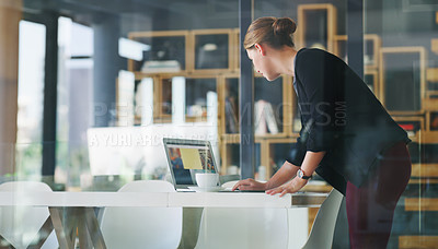 Buy stock photo Cropped shot of an attractive young businesswoman standing alone in her office and typing on her laptop