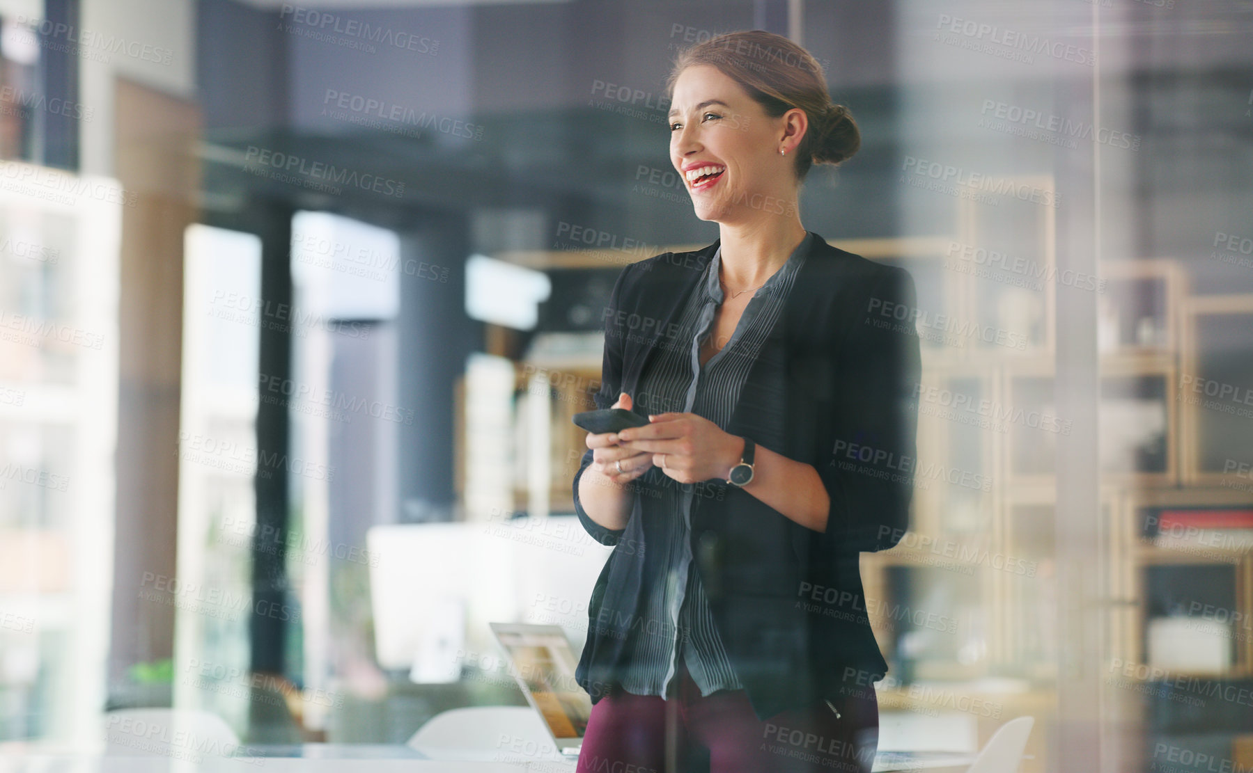 Buy stock photo Cropped shot of an attractive young businesswoman standing alone in her office and texting on her cellphone