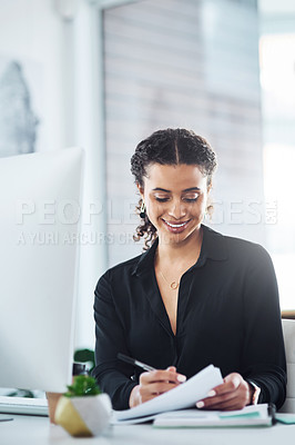 Buy stock photo Shot of a young businesswoman writing notes while working in an office