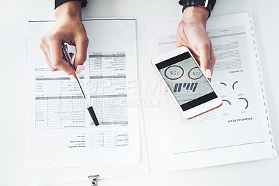 Buy stock photo Closeup shot of an unrecognisable businesswoman using a cellphone while going through paperwork in an office