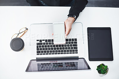 Buy stock photo Closeup shot of an unrecognisable businesswoman using a cellphone while working on a laptop in an office