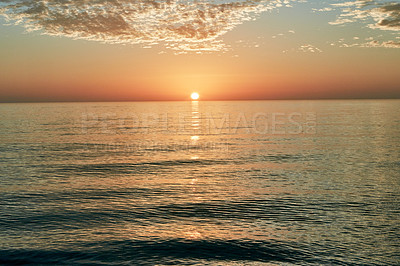 Buy stock photo Shot of the sun setting over the ocean