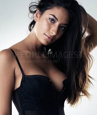 Buy stock photo Cropped portrait of an attractive young woman posing seductively against a gray background in the studio