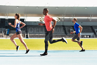 Buy stock photo Full length shot of three young athletes running along the track together