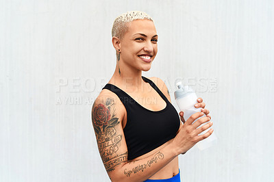 Buy stock photo Cropped portrait of an attractive young female athlete drinking water against a grey background