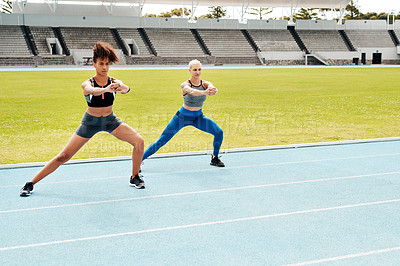 Buy stock photo Full length shot of two young attractive athletes standing together and holding side lunges outside on a running track