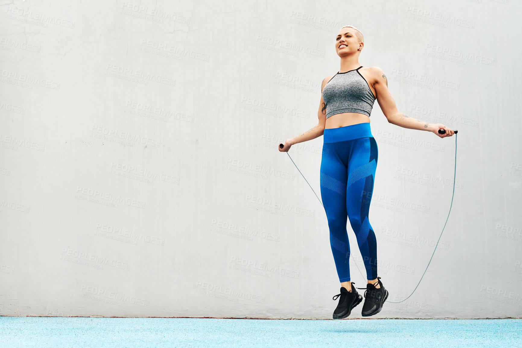 Buy stock photo Jump, rope and woman skipping against space in stadium for sports, workout practice and cardio. Performance, health and body with female athlete training on track for strong, mockup and exercise