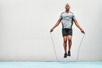 Buy stock photo Jump, rope and training with black man skipping in stadium for sports, workout practice and cardio. Health and body with athlete jumping on track for strong, mockup space and exercise against wall