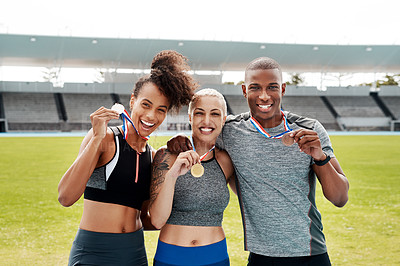 Buy stock photo Cropped portrait of a diverse group of athletes standing together and holding up medals after winning a running race