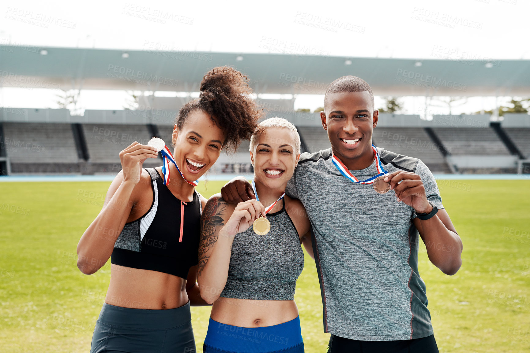 Buy stock photo Cropped portrait of a diverse group of athletes standing together and holding up medals after winning a running race