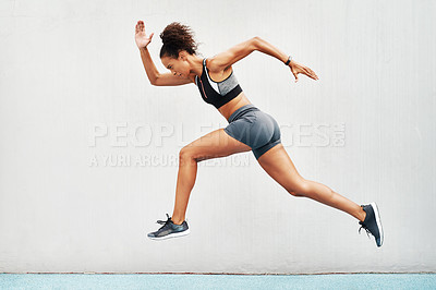 Buy stock photo Full length shot of an attractive young athlete jumping while on a track field during an outdoor workout session