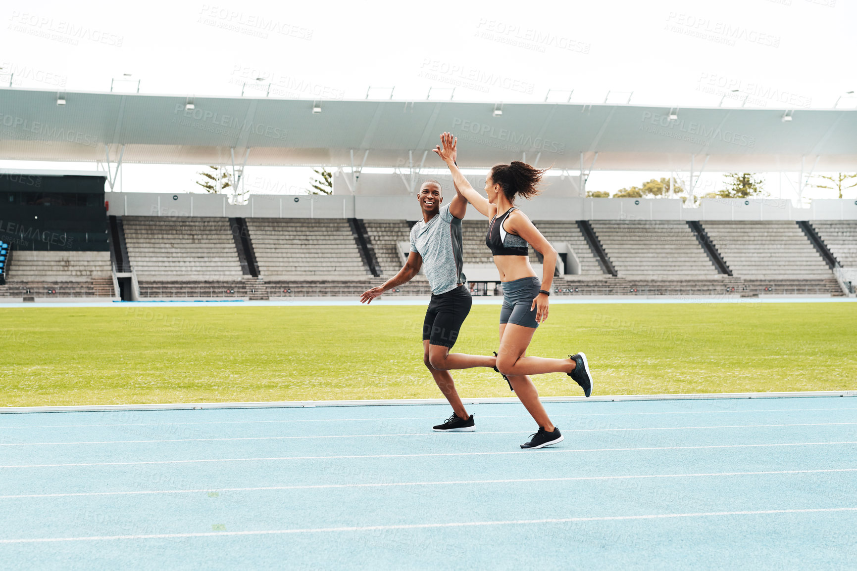 Buy stock photo Man, woman and high five for running on track for exercise, fitness and race in stadium. Male athlete, female personal trainer and success in arena for contest, competition and achievement or victory