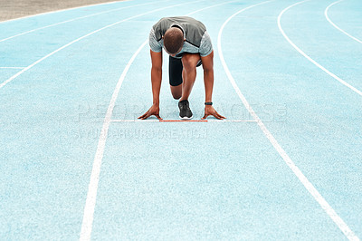 Buy stock photo Full length shot of an unrecognizable athlete crouching down and preparing to sprint along a track during a training session