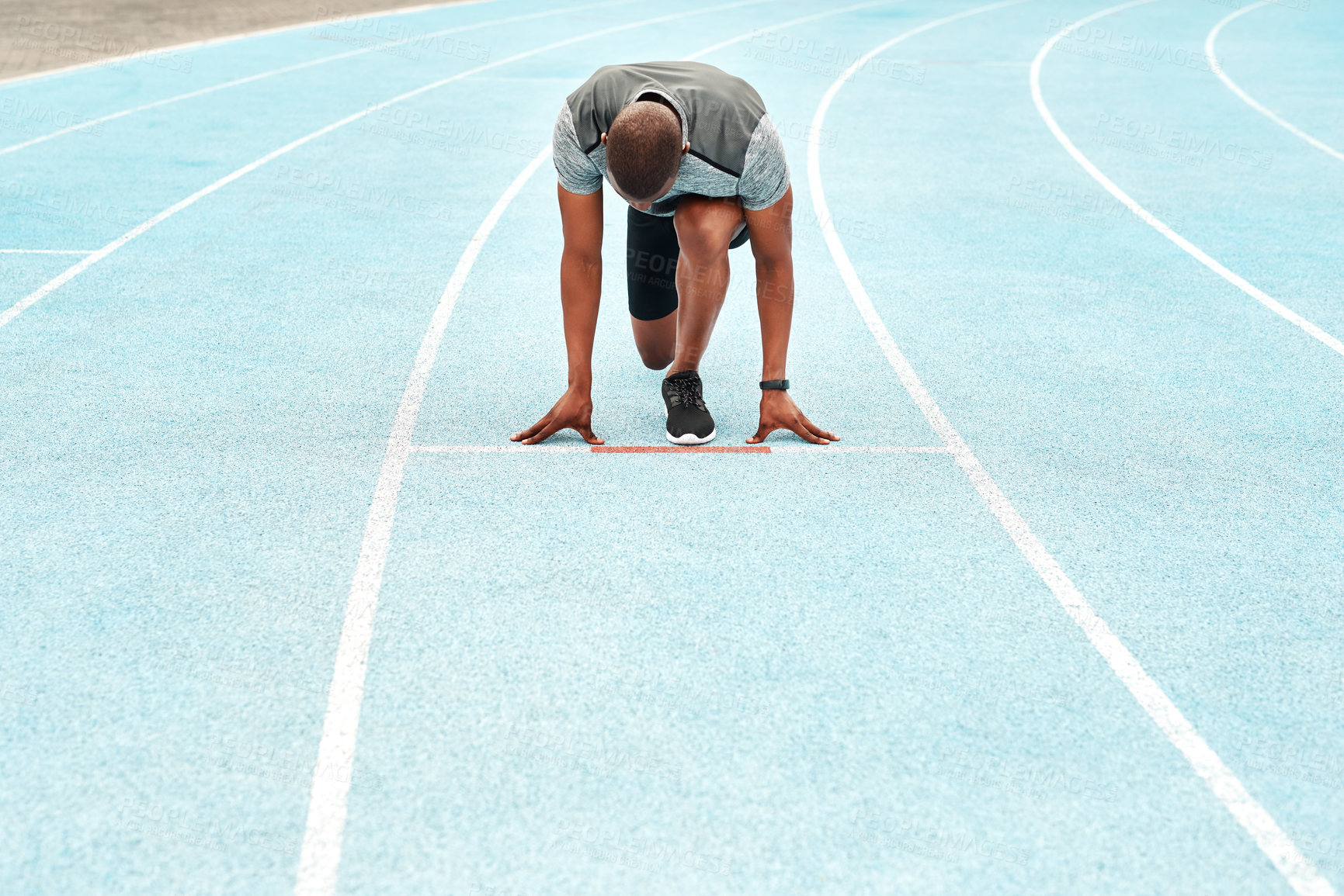 Buy stock photo Full length shot of an unrecognizable athlete crouching down and preparing to sprint along a track during a training session