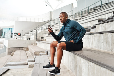 Buy stock photo Fitness, phone and man thinking on stadium steps for training break, pause or social media scroll. Arena, stairs and runner with smartphone search, streaming or app for planning marathon workout