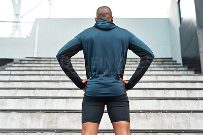 Buy stock photo Rearview shot of an unrecognizable young athlete standing akimbo before running up a flight of stairs during a workout
