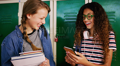 Buy stock photo Cropped shot of two young school kids browsing on a cellphone together while waiting to go to class inside of a school