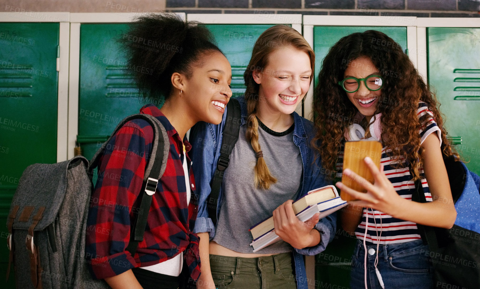 Buy stock photo Cropped shot of a group of young school kids browsing on a cellphone together while waiting to go to class inside of a school