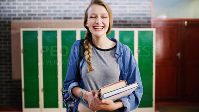 Buy stock photo Cropped shot of a cheerful young school kid holding her books while waiting to go to class inside of a school during the day