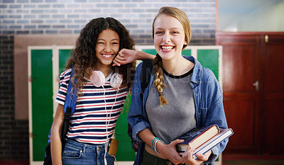 Buy stock photo Portrait of two cheerful young school kids standing together smiling brightly while waiting to go to class inside of a school during the day