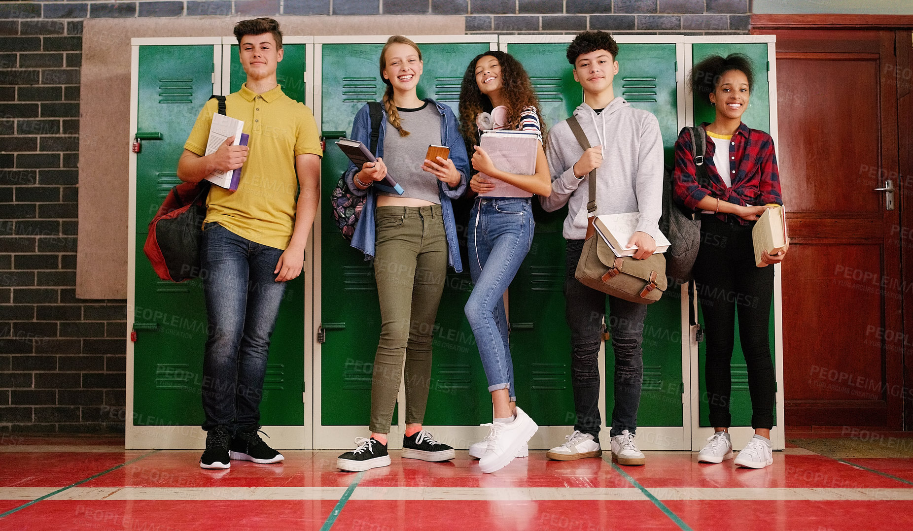 Buy stock photo Portrait of a group of cheerful young school kids talking to each other before class inside of a school during the day