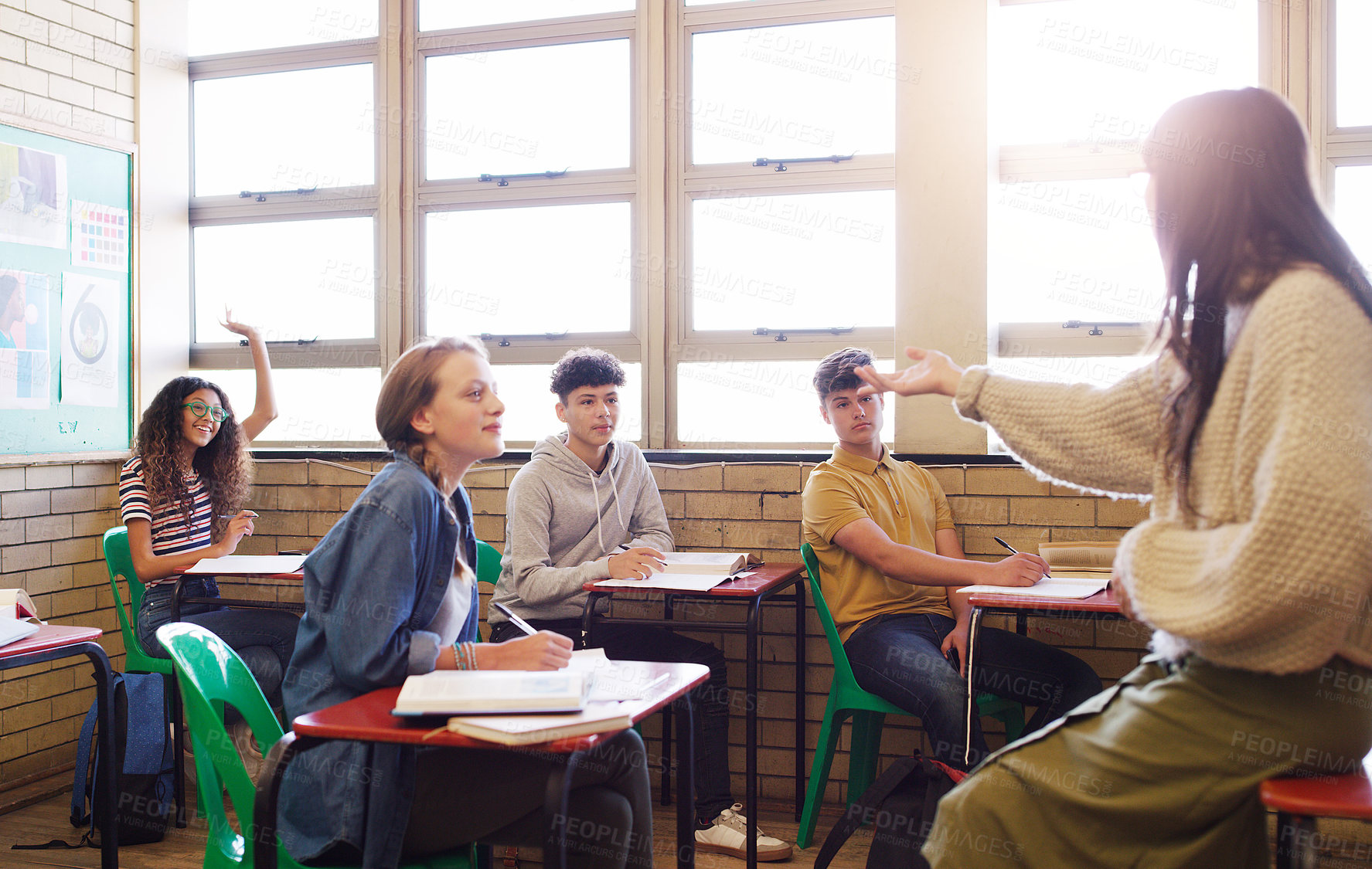 Buy stock photo Cropped shot of a cheerful young teacher giving class to a group of school kids inside of a school during the day