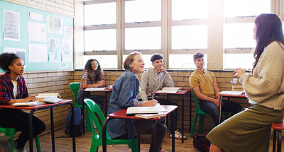 Buy stock photo Cropped shot of a cheerful young teacher giving class to a group of school kids inside of a school during the day