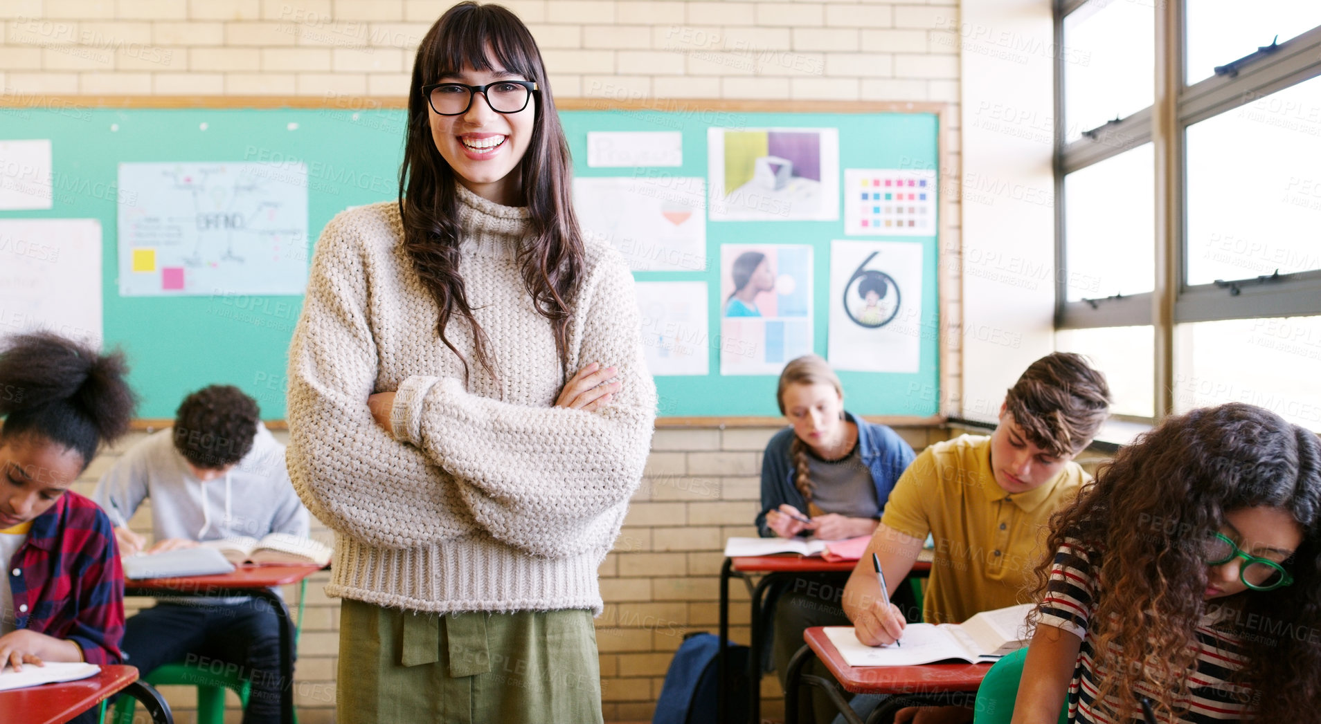 Buy stock photo Portrait of a cheerful young teacher giving class to a group of students inside of a school during the day