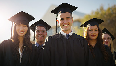 Buy stock photo Portrait of a group of cheerful young students standing together on graduation day outside during the day