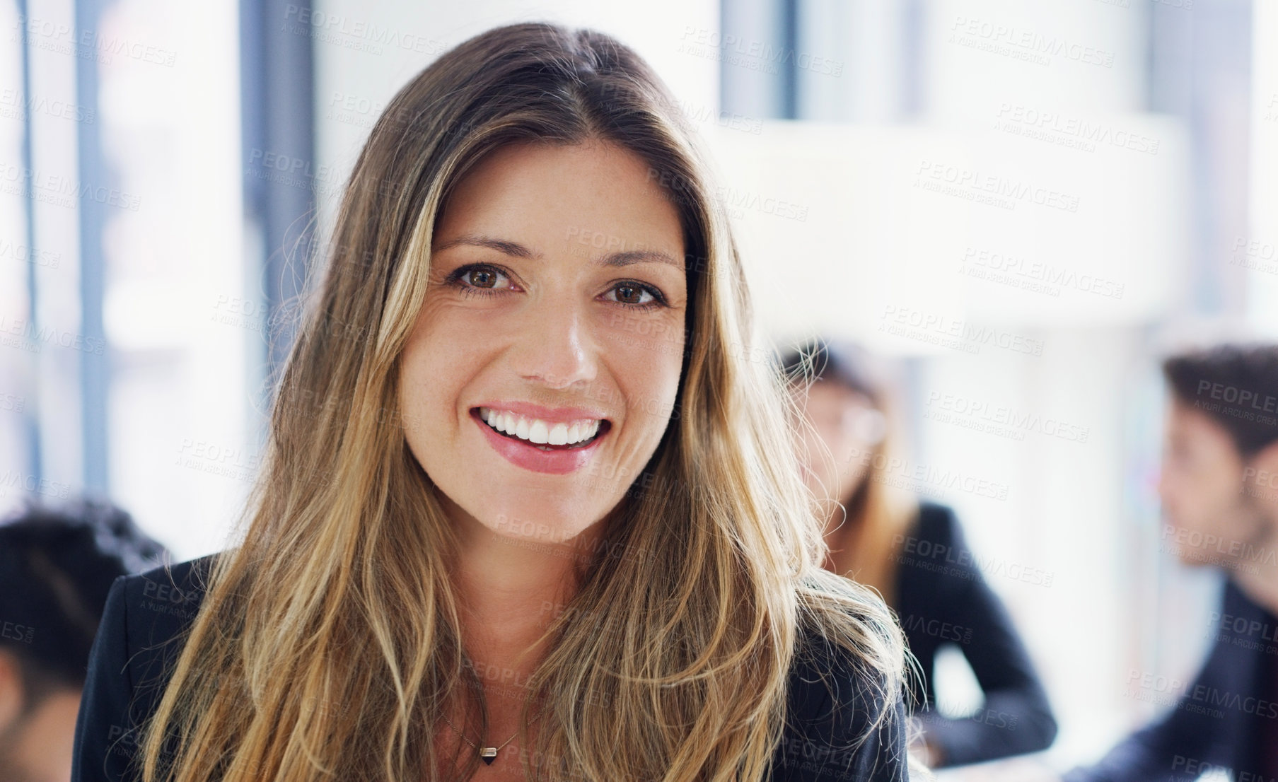 Buy stock photo Portrait of a young businesswoman sitting in an office with her colleagues in the background