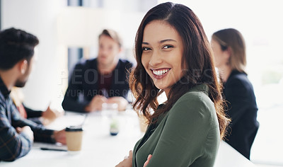 Buy stock photo Portrait of a young businesswoman sitting in an office with her colleagues in the background