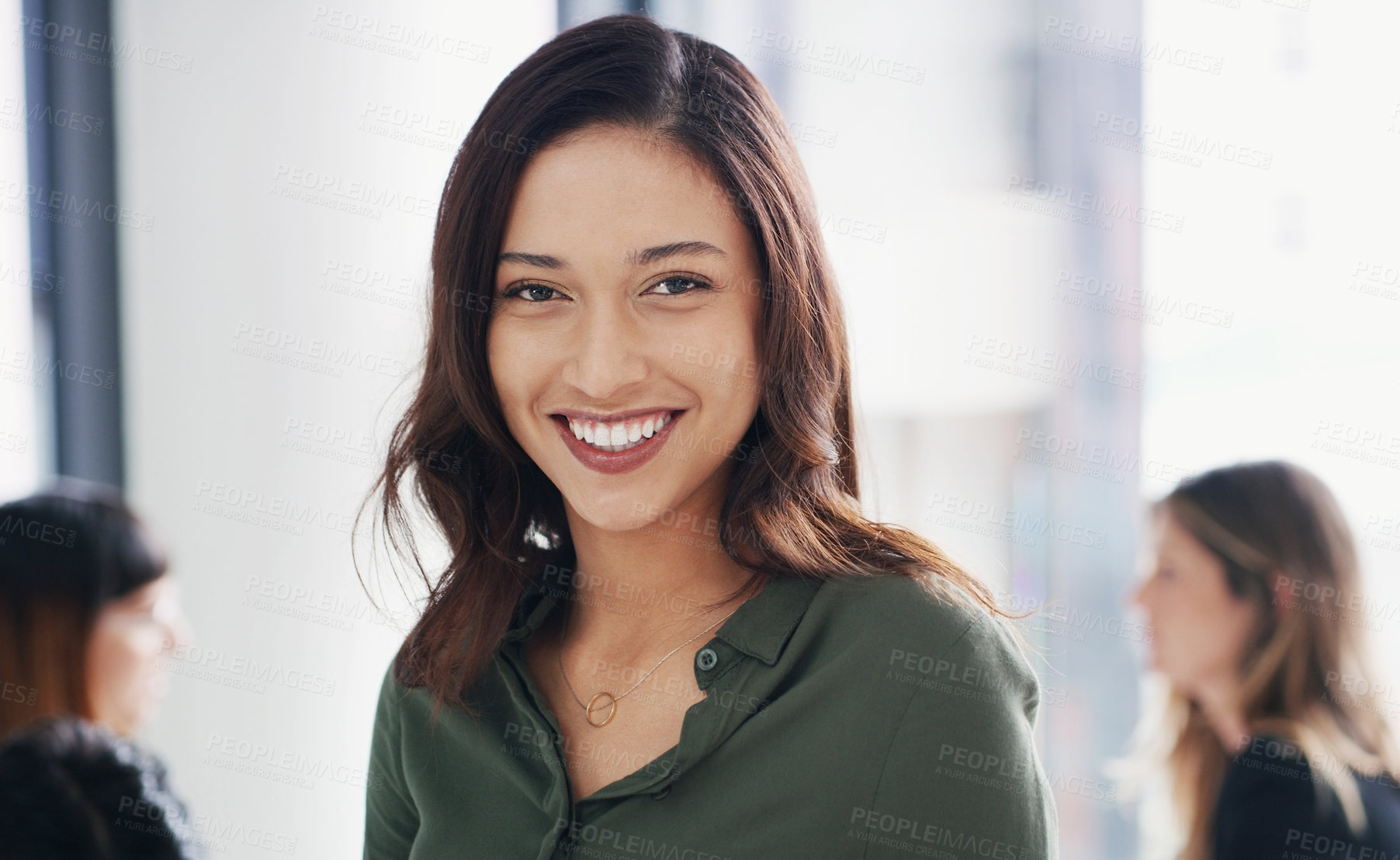 Buy stock photo Portrait of a young businesswoman sitting in an office with her colleagues in the background