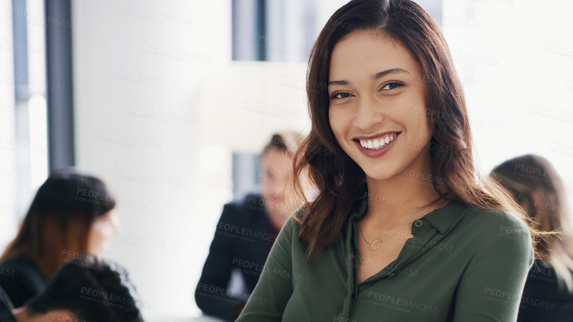 Buy stock photo Portrait of a young businesswoman sitting in an office with her colleagues in the background