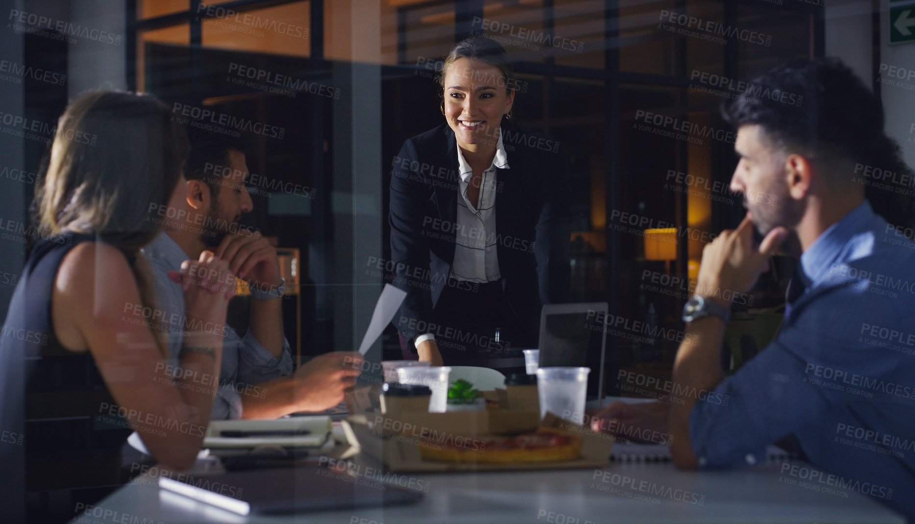 Buy stock photo Cropped shot of a diverse group of businesspeople sitting together and having a meeting in the office late at night